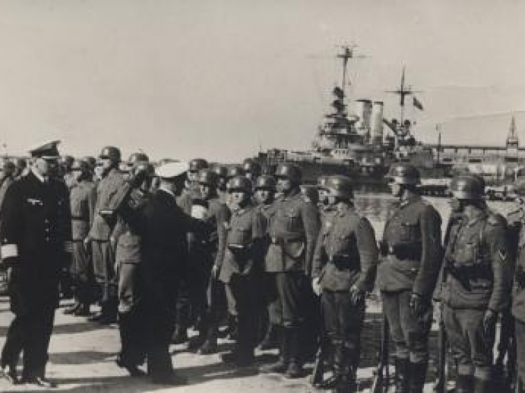Admirał Erich Raeder pozdrawia oddziały uczestniczące w zdobyciu Westerplatte. Na drugim planie widoczny „Schleswig Holstein”. Westerplatte, 18.09.1939 r. Fot. CAW