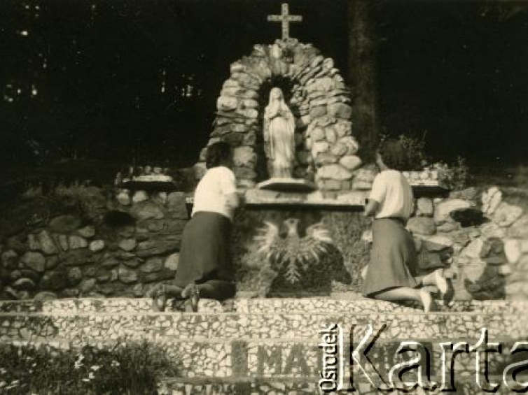 Sierpień 1943, Rumunia. Dwie kobiety modlące się przy figurze Matki Boskiej ustawionej w kamiennej kapliczce, pod figurą ułożony z kamieni Biały Orzeł, na prowadzących do kapliczki schodach data: "Maj 1940". Fot. NN, zbiory Ośrodka KARTA, udostępnił Jon Pascu.