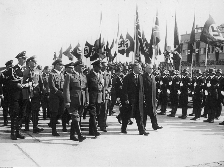 Konferencja czterech mocarstw w Monachium - powitanie premiera Wielkiej Brytanii Neville'a Chamberlaina na lotnisku: przed frontem kompanii honorowej przechodzą m.in.: minister spraw zagranicznych Niemiec Joachim Ribbentrop (1. z prawej) i premier Neville Chamberlain (2. z prawej). Fot. NAC