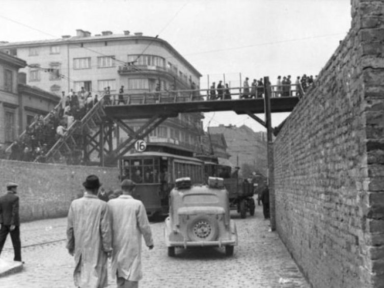 Getto warszawskie: Ulica Chłodna przy skrzyżowaniu z ul. Żelazną. Na zdjęciu widoczny drewniany most łączący Małe i Duże Getto. 06.1942. Źródło: Wikimedia Commons/Bundesarchiv