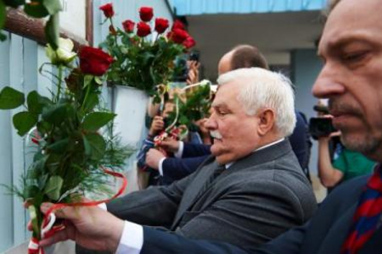 Lech Wałęsa w towarzystwie min. Bogdana Zdrojewskiego przypina kwiaty do bramy Stoczni Gdańskiej Fot. PAP/A.Warżawa