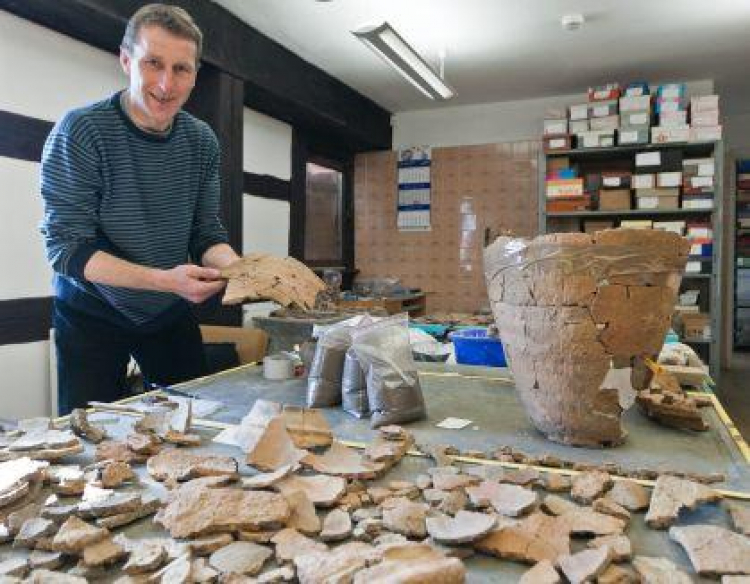 Archeolog Paweł Kaźmierczak prezentuje opracowywane fragmenty naczyń z okresu kultury łużyckiej. Fot. PAP/P. Kaźmierczak