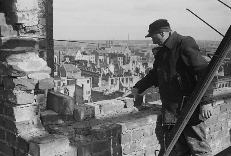 Odbudowa Bazyliki Mariackiej Wniebowzięcia Najświętszej Marii Panny - prace nad rekonstrukcją dachu świątyni; w tle ruiny Głównego Miasta i wyspa Ołowianka. Gdańsk, 1948 r. Fot. PAP/CAF