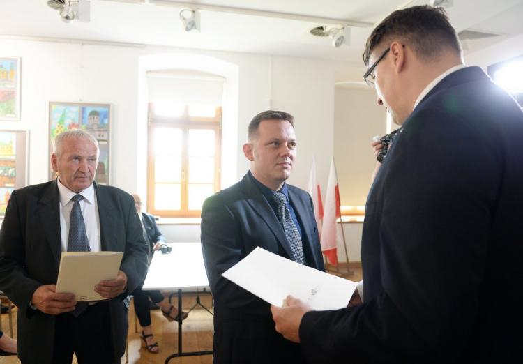 Przedstawiciele rodzin zamordowanych żołnierzy antykomunistycznego podziemia Jan Pecel (L) oraz Marcin Popiel (C) odbierają noty identyfikacyjne z rąk prezesa Fundacji Niezłomni Wojciecha Łuczaka (P). Fot. PAP/P. Polak