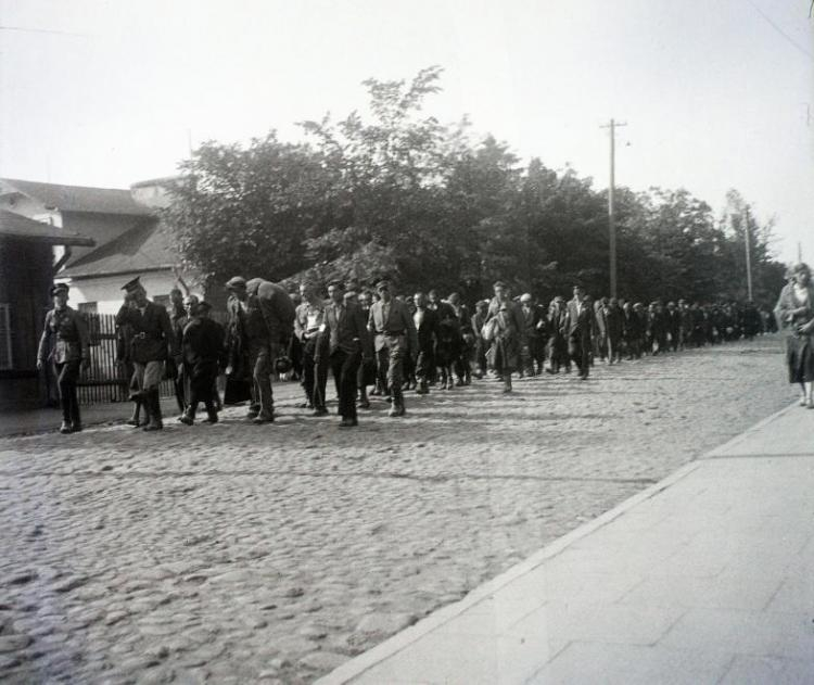 Ulica Batorego w getcie w Skierniewicach, kolumna ludzi - prawdopodobnie robotników żydowskich prowadzonych do pracy. 1941 r. Fot. Bogdan Celichowski. Źródło: portal FORTEPAN