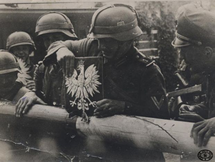 Żołnierze niemieccy zrywają godło Polski ze szlabanu granicznego. Przejście graniczne w Kolibkach, 01.09.1939. Źródło: CAW