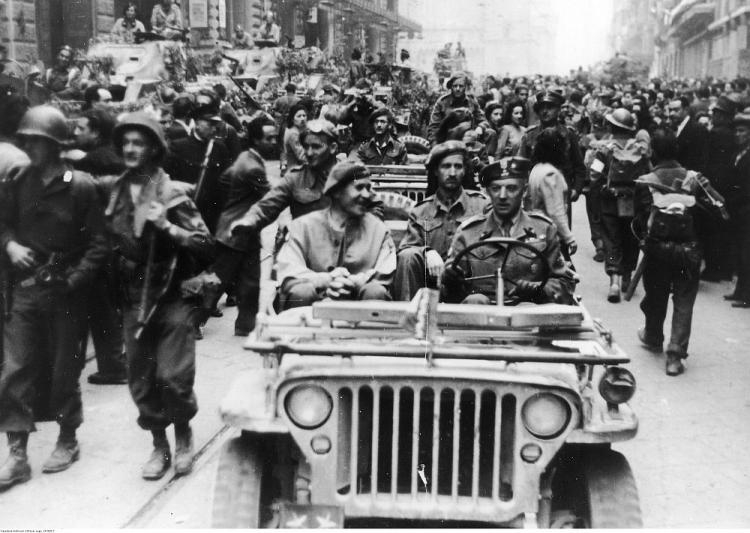 Wkroczenie 2. Korpusu Polskiego do Bolonii: generałowie Zygmunt Szyszko-Bohusz (1. z lewej) i Klemens Rudnicki (za kierownicą) w samochodzie Willys MB; z lewej strony widoczne samochody pancerne T17 (Staghound). 21.04.1945. Fot. NAC