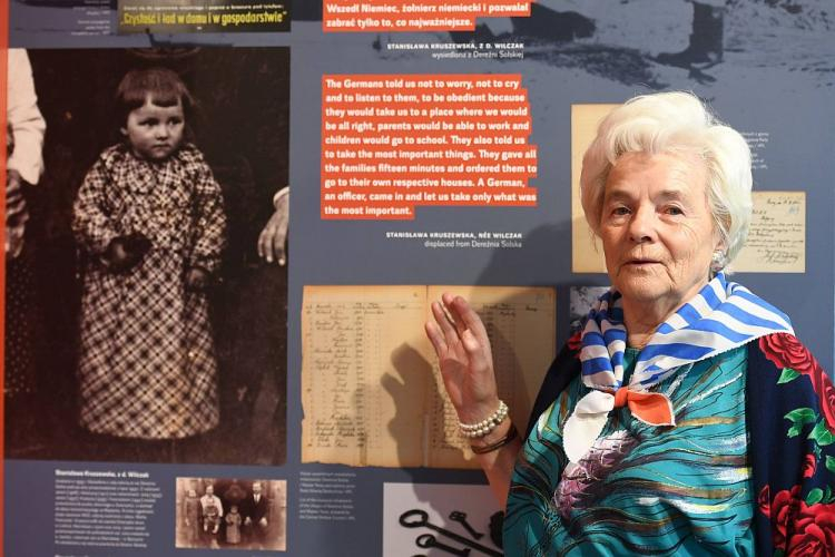 Stanisława Kruszewska, która jako 8-latka, w 1943 r. została wysiedlona z wsi Dereźnia Solska i trafiła do obozu na Majdanku, stoi przy swoim zdjęciu z dzieciństwa prezentowanym na wystawie "Wysiedleńcy z Zamojszczyzny w obozie na Majdanku" w Muzeum na Majdanku. Fot. PAP/W. Pacewicz
