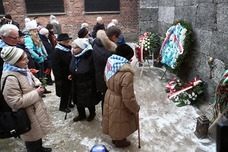 Byli więźniowie niemieckich obozów złożyli kwiaty i zapalili znicze pod Ścianą Śmierci na terenie b. obozu Auschwitz. 27.01.2019. Fot. PAP/Ł. Gągulski