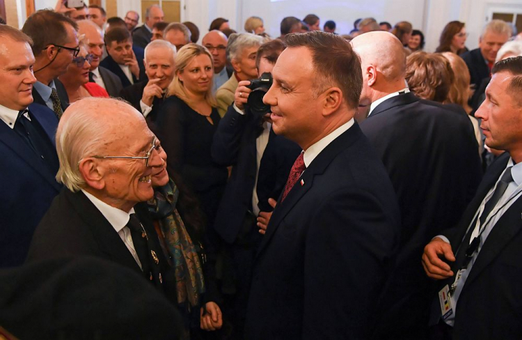 Prezydent Andrzej Duda (C) oraz syn generała Maczka Andrzej (L) podczas spotkania z przedstawicielami Polonii połączonego z ceremonią wręczenia odznaczeń państwowych w ambasadzie RP w Brukseli. Fot. PAP/P. Nowak