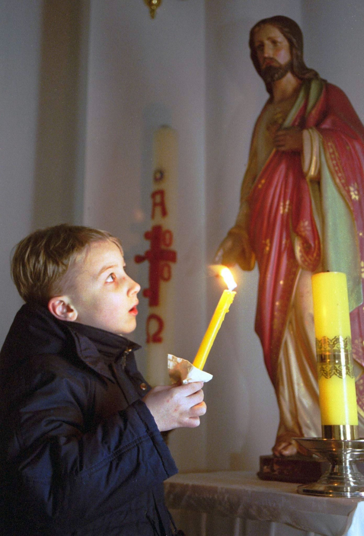 Mińsk, Białoruś, 26.12.2000. Chłopiec trzyma świecę w czasie mszy wigilijnej dla dzieci w kościele rzymsko-katolickim w Mińsku w niedzielę, 24 bm. Fot. PAP/EPA/W. Draczew