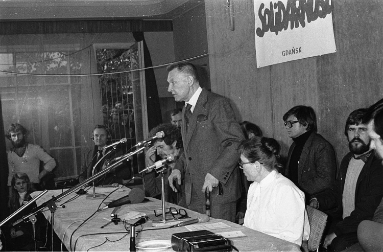 Konferencja prasowa gdańskiej „Solidarności”: przemawia Lech Bądkowski, rzecznik prasowy „S”; przy stole z lewej Bogdan Lis, z prawej Anna Walentynowicz; z tyłu Andrzej Celiński (3P). Gdańsk, 31.10.1980. Fot. PAP/CAF/S. Kraszewski