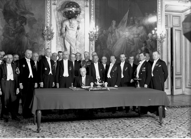 23 04 1935. Warszawa. Zamek Królewski, Sala Rycerska. Widoczni m.in. premier W. Sławek, M. Z. Kościałkowski, płk J. Głogowski, S. Świeżawski, wicemarszałek Sejmu S. Car, marszałek Sejmu K. Świtalski, marszałek Senatu W, Raczkiewicz, K. Romer (na prawo za W. Raczkiewiczem), M. Butkiewicz, E. Kaliński, H. Floyar-Rajchman (2. z lewej), J. Paciorkowski, J. Poniatowski, W. Jędrzejewicz, ks. J Humpola (stoi w głębi za prezydentem), kpt. J. Hartman (w głębi, na prawo za K. Romerem). Źródło: NAC