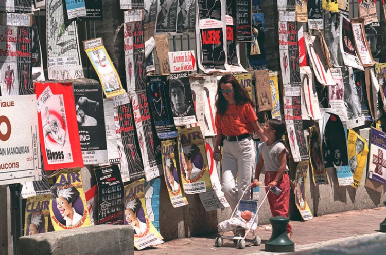 9 lipca 1996 r. Początek 50.  Międzynarodowego Festiwalu Teatralnego w Awinionie. N/z kobieta z dzieckiem przechodzą obok budynku zalepionego plakatami anonsującymi festiwalowe przedstawienia. Fot. PAP/EPA