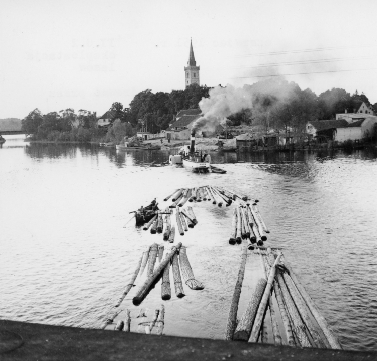 Mikołajki, lata 50. Spław drewna przez jezioro Mikołajskie; w oddali widoczne Mikołajki i kościół św. Trójcy. PAP/CAF