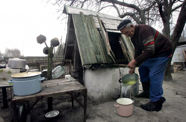 Ilintsy, Ukraina, 23.04.06. Michaił Ratkiewicz, mieszkaniec wsi Ilintsy, około 20 km od elektrowni czarnobylskiej, nabiera wodę przed swym domem. Ponad 330 mieszkańców zagrożonych promieniowaniem odmówiło zmiany miejsca zamieszkania w 1986 roku po eksplozji reaktora nr 4 i wybrało życie 30 km od miejsca wybuchu. Fot. PAP/EPA