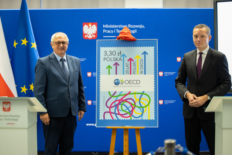 Wiceminister rozwoju i technologii Grzegorz Piechowiak (L) oraz prezes Poczty Polskiej Tomasz Zdzikot (P) podczas prezentacji znaczka okolicznościowego „25 lat Polski w OECD”. Źródło: www.twitter.com/PocztaPolska