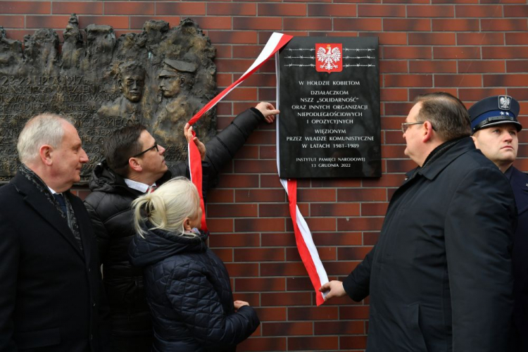  Gdańsk, 13.12.2022. Szef Urzędu do Spraw Kombatantów i Osób Represjonowanych J.J. Kasprzyk (2P), wojewoda pomorski D. Drelich (P), dyrektor Oddziału IPN w Gdańsku dr P. Warot (2L) oraz skazana na 10 lat więzienia w czasie stanu wojennego E. Kubasiewicz (L) uczestniczą w odsłonięciu przy bramie Aresztu Śledczego w Gdańsku tablicy dedykowanej bohaterkom opozycji demokratycznej w okresie „Solidarności” oraz innych organizacji niepodległościowych i opozycyjnych więzionym przez władze komunistyczne w latach 198