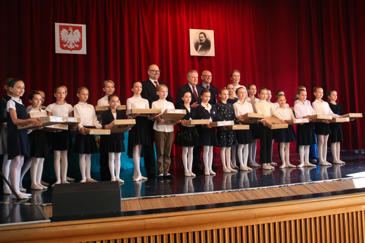 Minister kultury Piotr Gliński (2L-góra), podsekretarz stanu w Ministerstwie Cyfryzacji Paweł Lewandowski (L-góra) i dyrektor szkoły Faustyna Gałązka (P-góra) podczas uroczystego przekazania laptopów czwartoklasistom z Ogólnokształcącej Szkoły Baletowej im. Romana Turczynowicza w Warszawie, w ramach programu Laptop dla Ucznia. Fot. PAP/A. Zawada