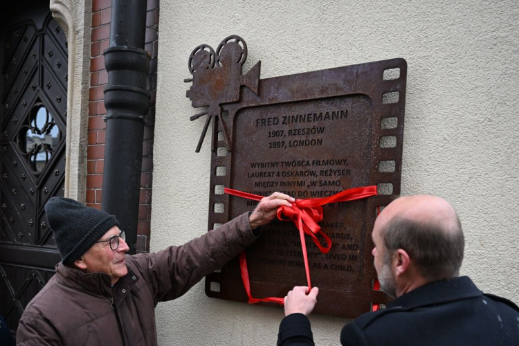 Rzeszów, 11.12.2023. Prezydent Rzeszowa Konrad Fijołek (P) i syn Freda Zinnemanna Tim Zinnemann (L) podczas odsłonięcia tablicy pamiątkowej Freda Zinnemanna, na fasadzie kamienicy przy ul. Rynek 3. Fot. PAP/D. Delmanowicz