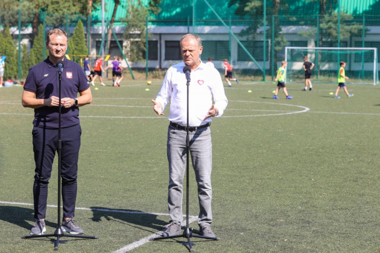 Premier Donald Tusk (C) i minister sportu i turystyki Sławomir Nitras (L) na konferencji prasowej na Boisku Orlik w Karczewie. Fot. PAP/R. Guz