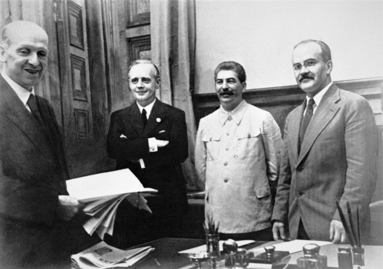 Od lewej stoją: szef działu prawnego niemieckiego MSZ Friedrich Gauss, niemiecki minister spraw zagranicznych Joachim von Ribbentrop, Józef Stalin oraz ludowy komisarz (minister) spraw zagranicznych ZSRR Wiaczesław Mołotow. 23 sierpnia 1939 roku w Moskwie. Źródło: Wikimedia Commons