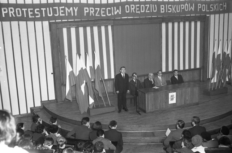 Warszawa 12.1965. Wiec protestacyjny studentów Szkoły Głównej Planowania i Statystyki (Szkoła Główna Handlowa) przeciwko orędziu biskupów polskich skierowanemu do biskupów niemieckich. W spotkaniu, odbywającym się w Auli Głównej SGPiS, uczestniczy m.in. redaktor naczelny dziennika „Życie Warszawy” i poseł na Sejm PRL Henryk Korotyński (widoczny przy stole 3P). PAP/Henryk Rosiak