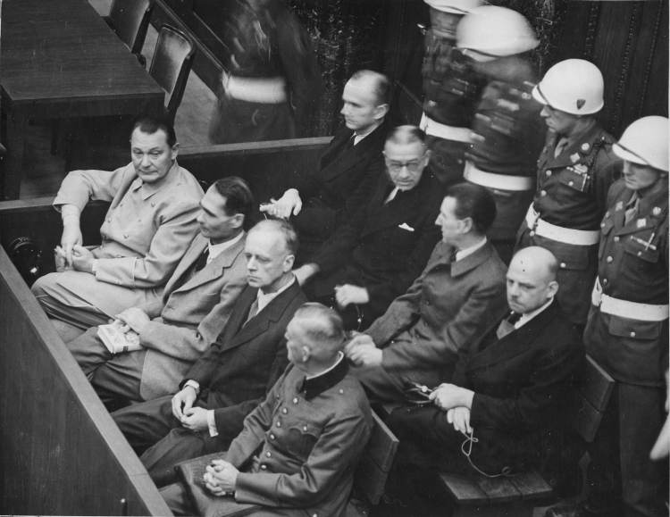 Ława oskarżonych podczas procesów norymberskich, 1945-1946 r. Fot. English: Work of the United States Government, Public domain, via Wikimedia Commons