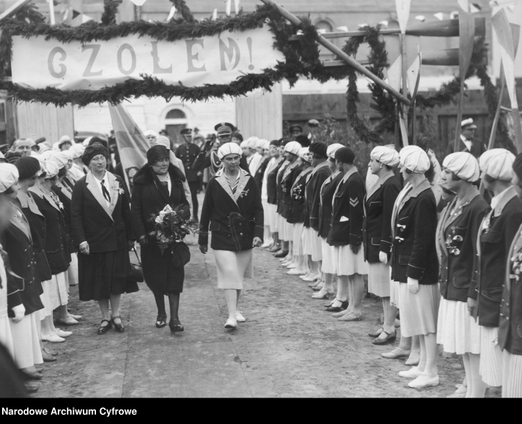 Michalina Mościcka (trzyma bukiet kwiatów) w towarzystwie dwóch kobiet przechodzi przed szpalerem wioślarek, lata 1927-1930. /NAC
