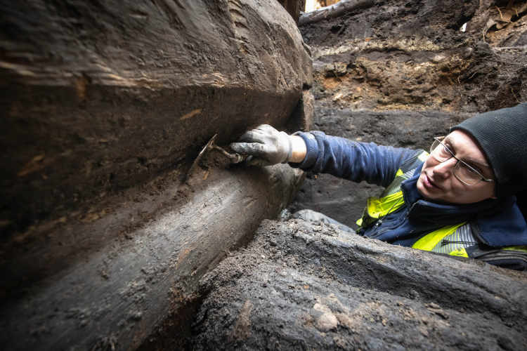 Archeolog toruńskiego Muzeum Okręgowego Jakub Henryk Dzieruk podczas prac przy fragmencie nieznanych wcześniej drewnianych konstrukcji z XIII w. odkrytych na dziedzińcu Domu Mikołaja Kopernika w Toruniu. Fot. PAP/Tytus Żmijewski