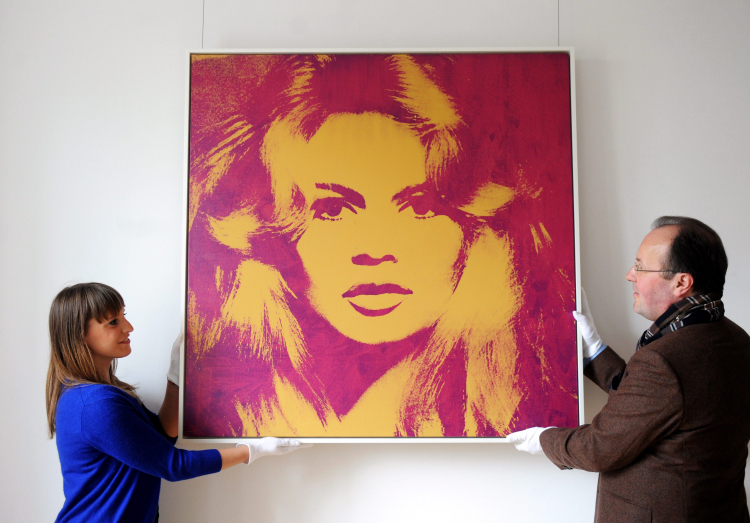 Pracownicy galerii Florian Sundheimer trzymają portret Brigitte Bardot autorstwa Andy'ego Warhola podczas prezentacji przedmiotów aukcyjnych Guntera Sachsa w Monachium, Niemcy, 23 kwietnia 2012 r. Fot. EPA/ANDREAS GEBERT Strona: PAP/EPA