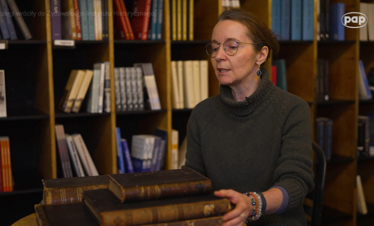 Jadwiga Jeż z Biblioteki ŻIH prezentuje odzyskane księgi. Fot. Screen/PAP Media