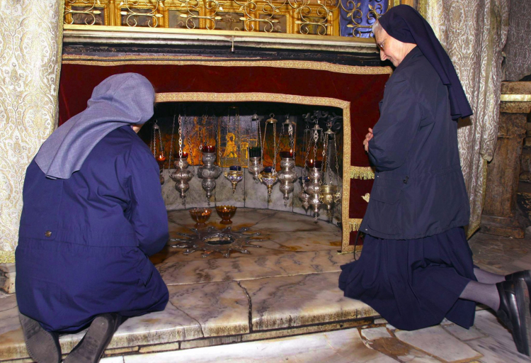 Zakonnice modlą się przed srebrną gwiazdą wskazującą dokładne miejsce narodzin Jezusa w Grocie Narodzenia pod Bazyliką Narodzenia Pańskiego w Betlejem. Fot. PAP/EPA/Abed Al Hafiz Hashlamoun