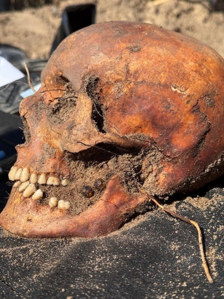 Zdjęcie z ekshumacji. Między zębami zmarłego widać paciorki różańca. Fot. Fundacja Latebra 