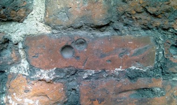 Dołki pokutne na murze kościoła. Fot. domena publicza