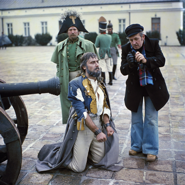 Andrzej Wajda (pierwszy od prawej), Janusz Kijowski w roli Waleriana Łukasińskiego (klęczy), Stanisław Gronkowski (w głębi) podczas realizacji spektaklu telewizyjnego według dramatu Stanisława Wyspiańskiego "Noc listopadowa", 1978 r. Fot. PAP/Jan Morek