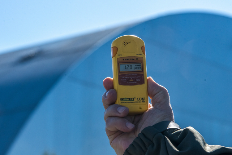 Dozymetr do pomiaru promieniowania na tle kopuły nad zniszczonym reaktorem elektrowni jądrowej w Czarnobylu. Fot. PAP/Vladyslav Musiienko