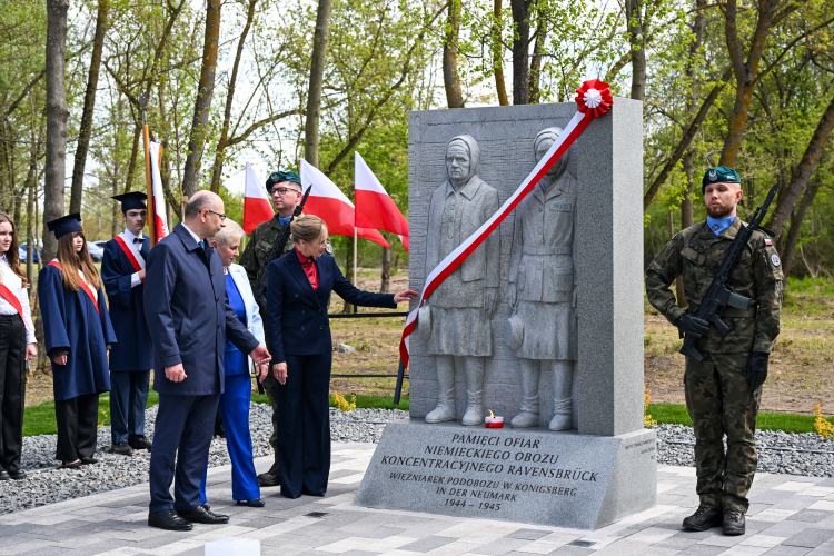 Pierwsza Dama Marta Nawrocka (trzecia od lewej), burmistrz Chojny Barbara Rawecka (druga od lewej) i wiceprezes IPN Mateusz Szpytma (pierwszy z lewej) podczas odsłonięcia pomnika upamiętniającego ofiary niemieckiego obozu koncentracyjnego Ravensbrück w Chojnie. Fot. PAP/Marcin Bielecki