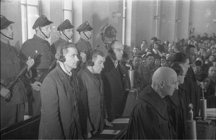 Warszawa, 1947-03-03. Odczytanie wyroku w procesie niemieckich zbrodniarzy wojennych (w drugim rzędzie): byłego szefa tzw. dystryktu warszawskiego Ludwika Fischera (1L), byłego starosty miejskiego w Warszawie Ludwika Leista (2L), byłego komendanta policji bezpieczeństwa Josefa Meisingera (3L) i płk. policji, byłego szefa wydziału w komendzie policji porządkowej Maksa Daume (4L). Proces przed Najwyższym Trybunałem Narodowym toczył się w dniach 17.12.1946 - 24 .02.1947. Nz. oskarżeni wysłuchują sentencji wyro