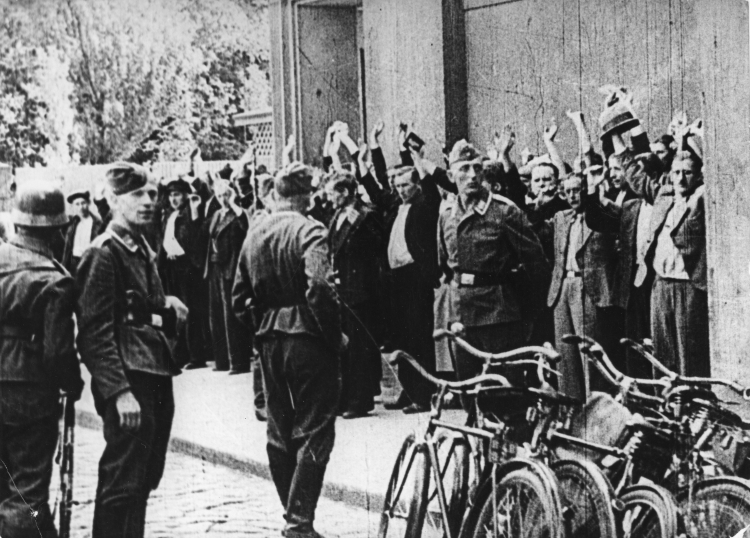 Niemieccy żołnierze przetrzymują ludność cywilną - ofiary ulicznej łapanki. Fot. PAP/CAF