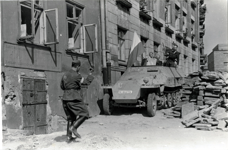 Wprowadzenie zdobytego transportera na teren powstańczy przez barykadę przy ul. Kopernika. Źródło: Wikipedia