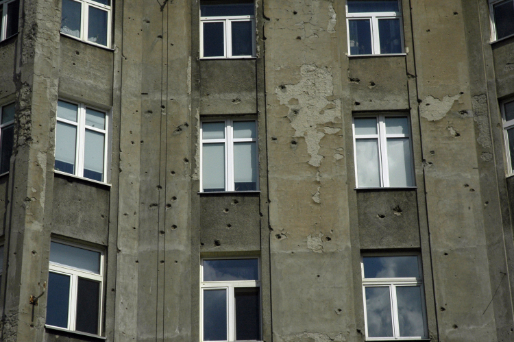 Dziury po pociskach w ścianie kamienicy przy ul. Chmielnej 73B róg Żelaznej (2014 r.). Fot Arch. PAP