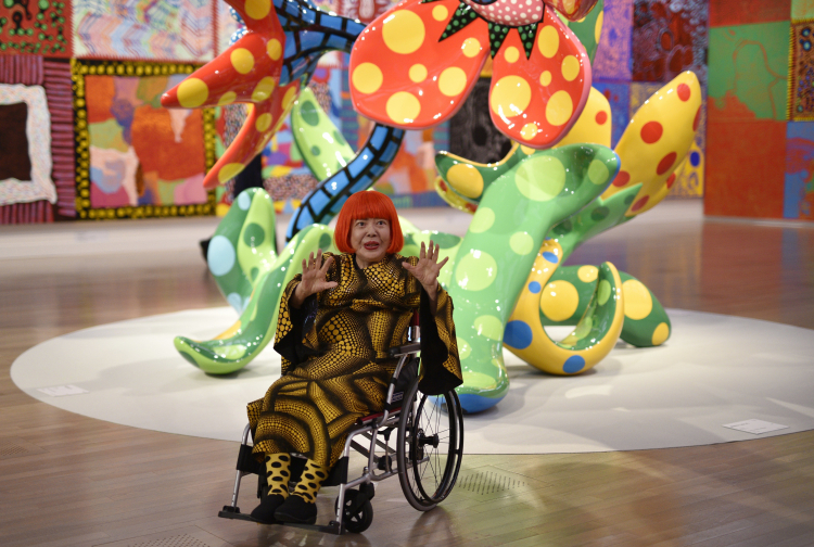 Japońska artystka Yayoi Kusama pozuje przed rzeźbami z serii "Kwiaty, które kwitną o północy" i "Kwiaty, które zakwitną jutro" w Narodowym Centrum Sztuki w Tokio w 2017 roku. Fot. PAP/EPA/FRANCK ROBICHON 